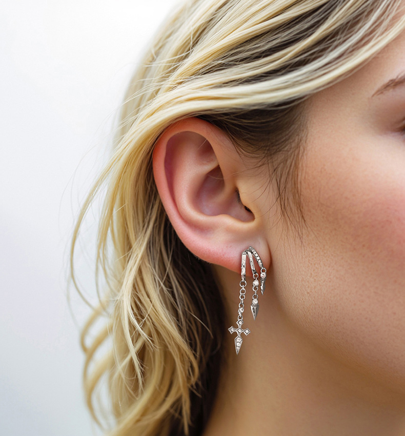 Close-up of a woman's ear wearing a S925 Sterling Silver Vermeil Naxos Illusion Earrings with dangling charms on a plain background