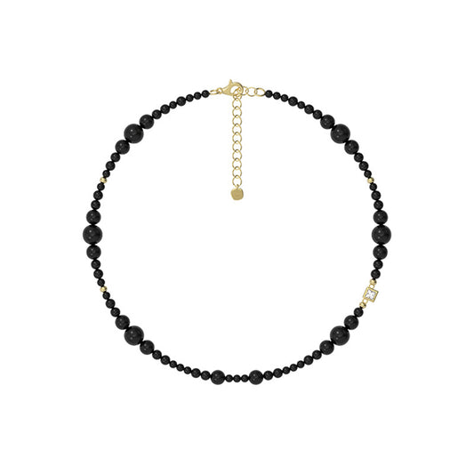 Black beaded necklace with gold clasp on a white background