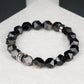 Black beaded bracelet with a silver clasp on a white surface