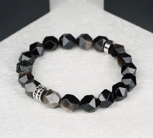 Black beaded bracelet with a silver clasp on a white surface