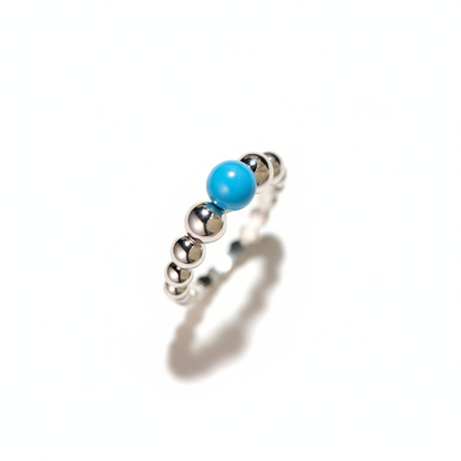 Silver ring with a turquoise bead on a white background