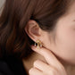 Close-up of a gold earring worn by a person with brown hair.