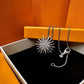 Two silver necklaces on a black tray with an orange background