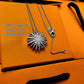 Silver necklace with a sunflower pendant on an orange jewelry box