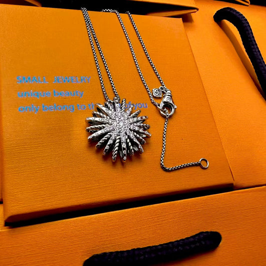 Silver necklace with a sunflower pendant on an orange jewelry box