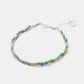 Bracelet with green and gold braided design on a white background