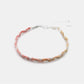 Braided bracelet with pink and beige strands on a white background