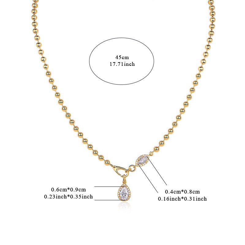 Gold necklace with a teardrop pendant and measurements on a white background