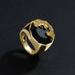 Gold ring with a black stone and dragon design on a dark background