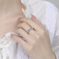 Close-up of a hand wearing a silver ring with gemstones on a white background