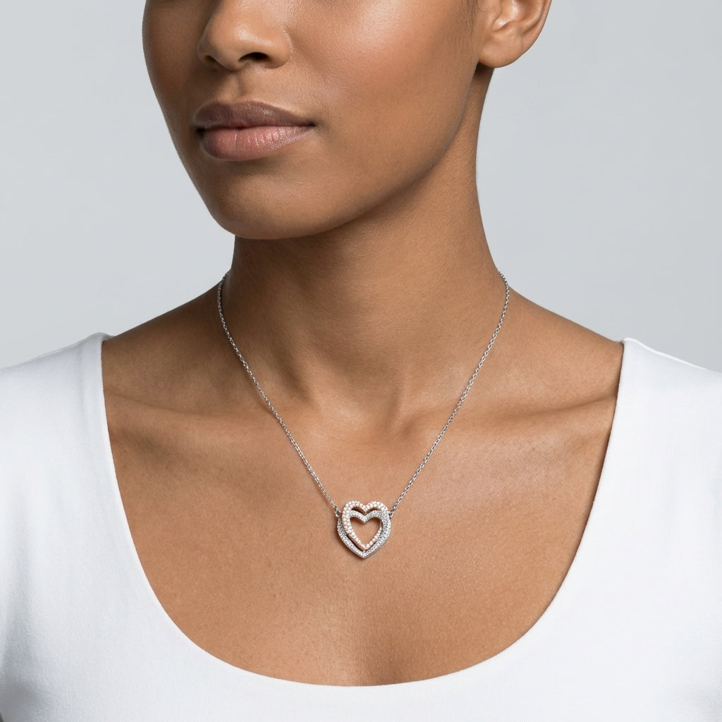 Woman wearing a silver heart-shaped necklace on a plain background