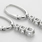 Close-up of silver earrings with diamond-like stones on a light gray background