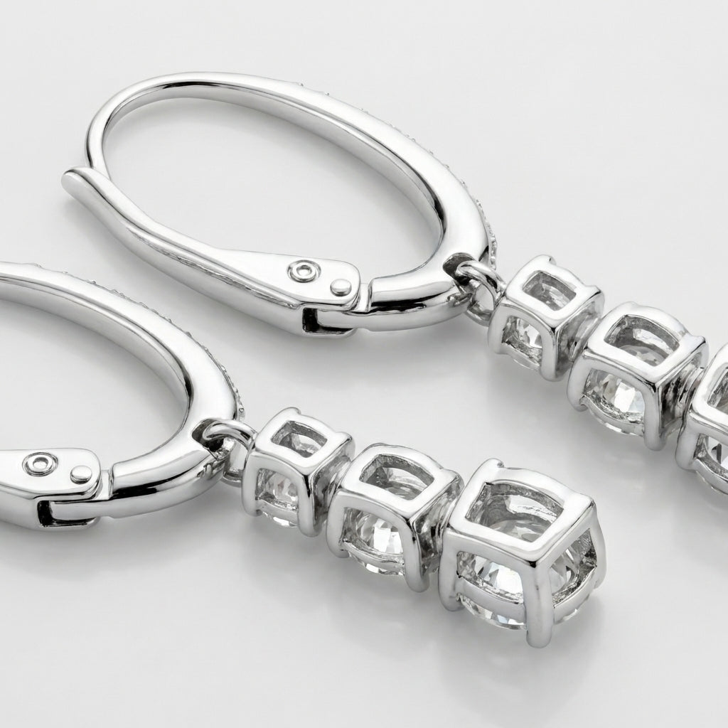 Close-up of silver earrings with diamond-like stones on a light gray background