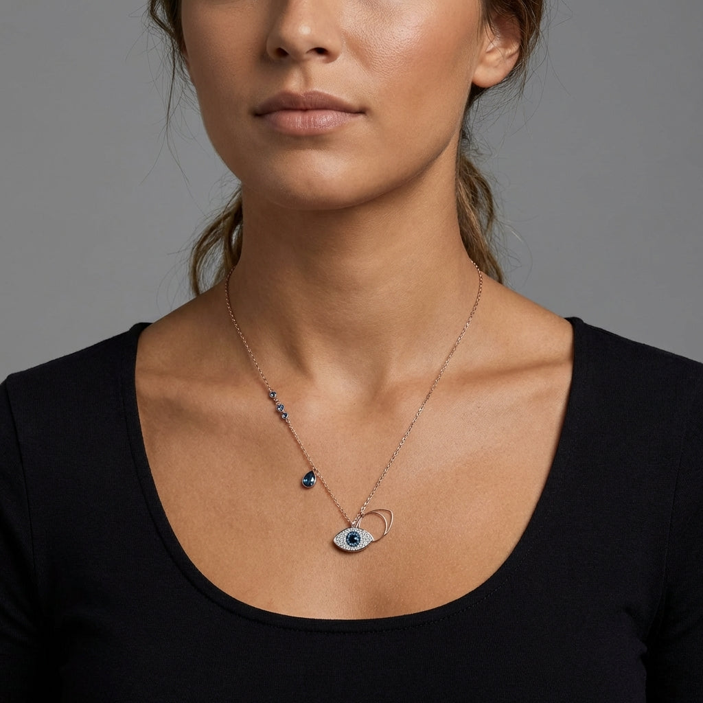 Woman wearing a necklace with an eye-shaped pendant against a gray background