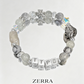 Beaded bracelet with letter beads and a cross charm on a light gray background, featuring the brand 'Zerra'.