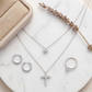 Silver jewelry set including necklace, ring, and earrings on a marble surface with a lavender branch.