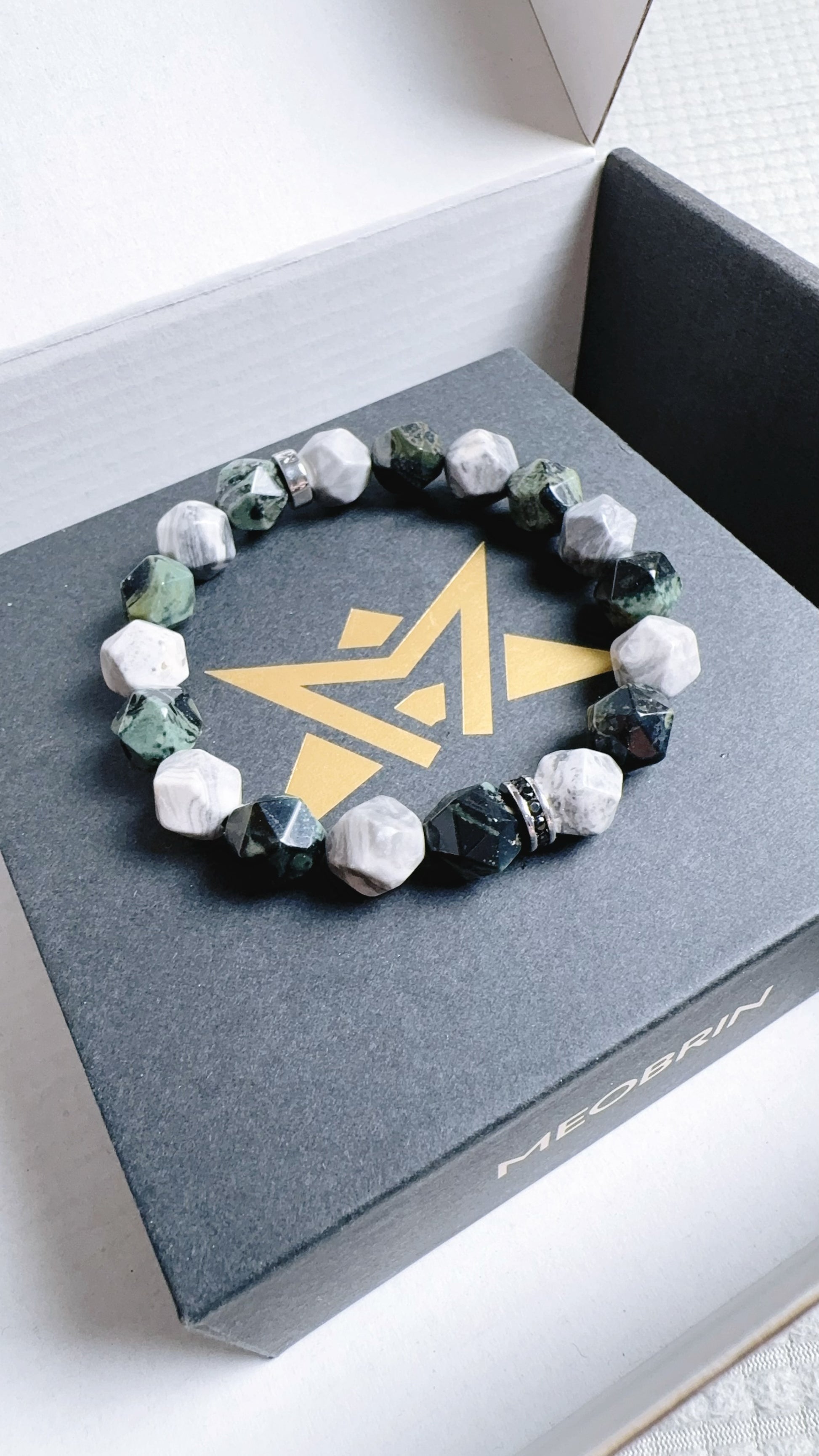 Bracelet with green and white stones on a branded box