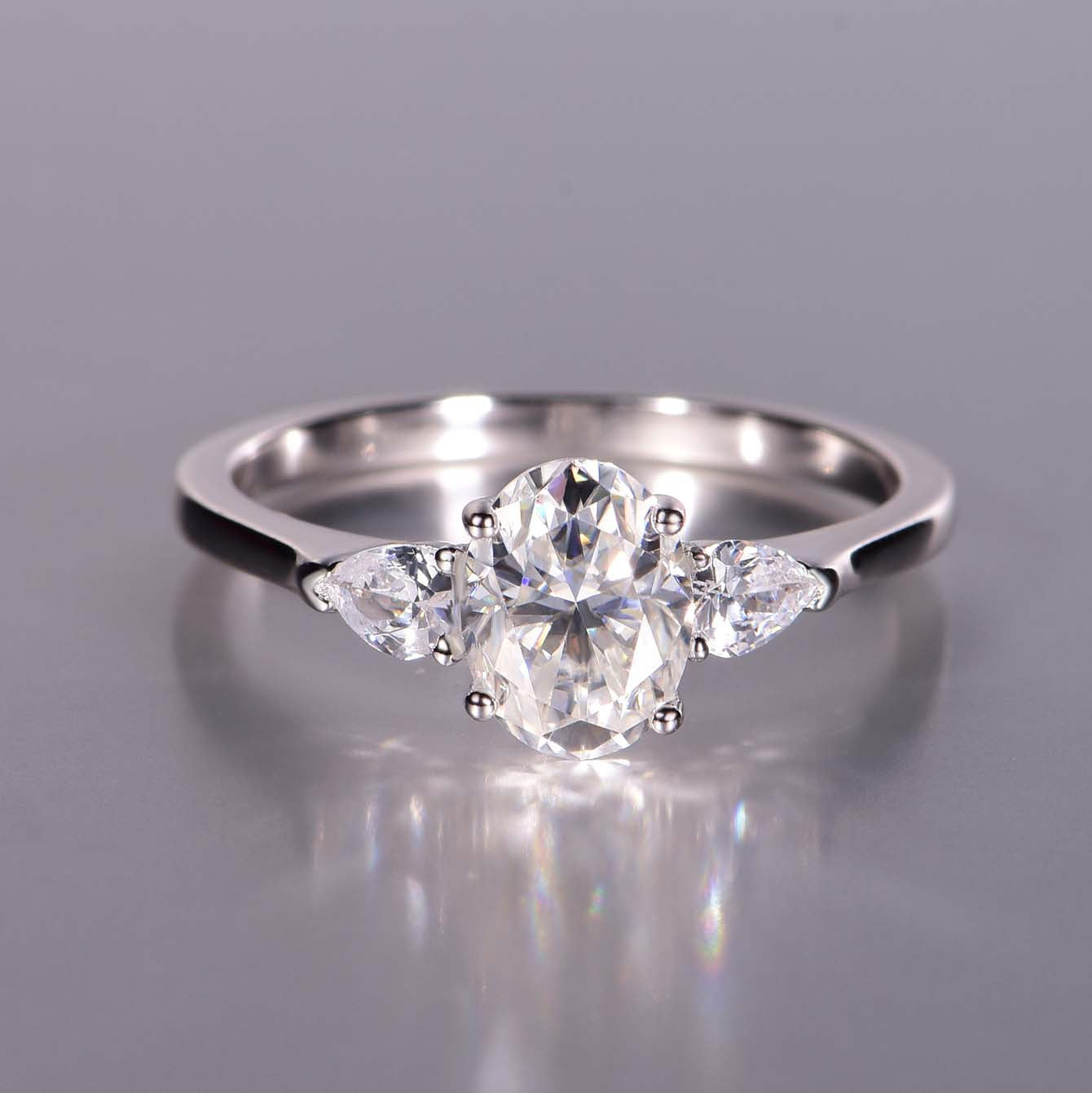 Romantic flat lay featuring 4–5 three stone rings on soft, timeless background. Alt: “Three Stone Oval Moissanite Engagement Rings – Past, Present, Future Collection.”