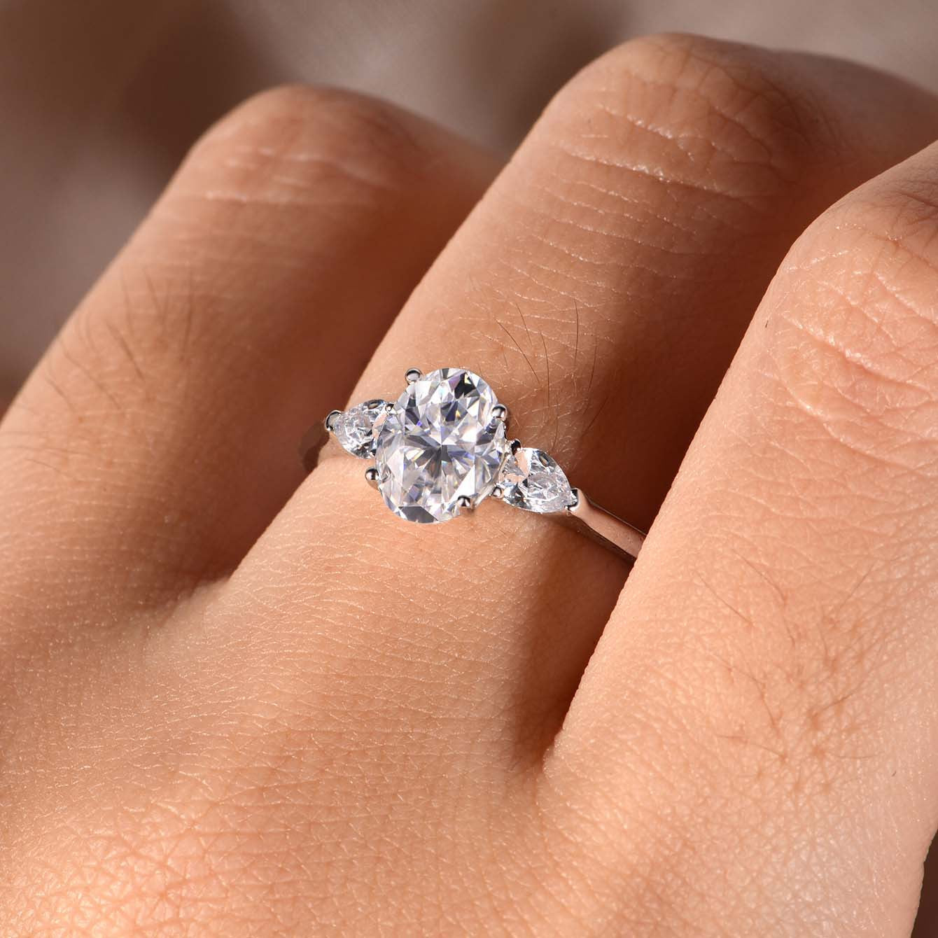 Romantic flat lay featuring 4–5 three stone rings on soft, timeless background. Alt: “Three Stone Oval Moissanite Engagement Rings – Past, Present, Future Collection.”