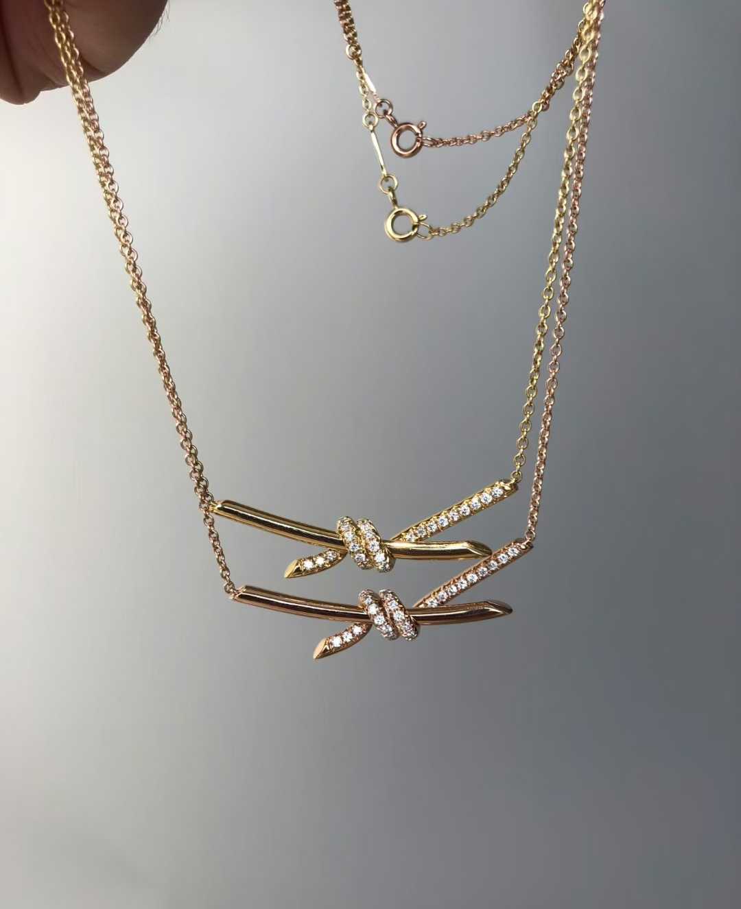 “Tiffany Knot pendant necklace in 18K gold flat lay”