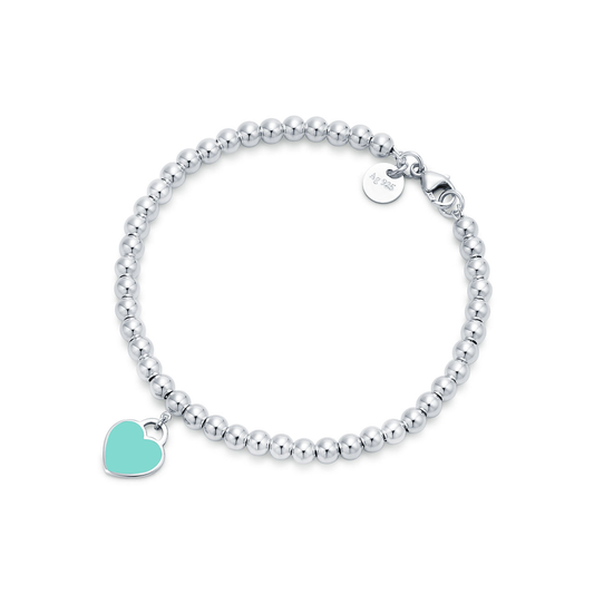 Silver beaded bracelet with a turquoise heart charm on a white background