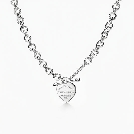 Silver necklace with heart-shaped tag and arrow pendant on a white background
