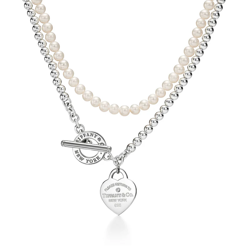 Pearl necklace with a silver toggle clasp and heart tag on a white background