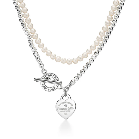 Pearl necklace with a silver toggle clasp and heart tag on a white background