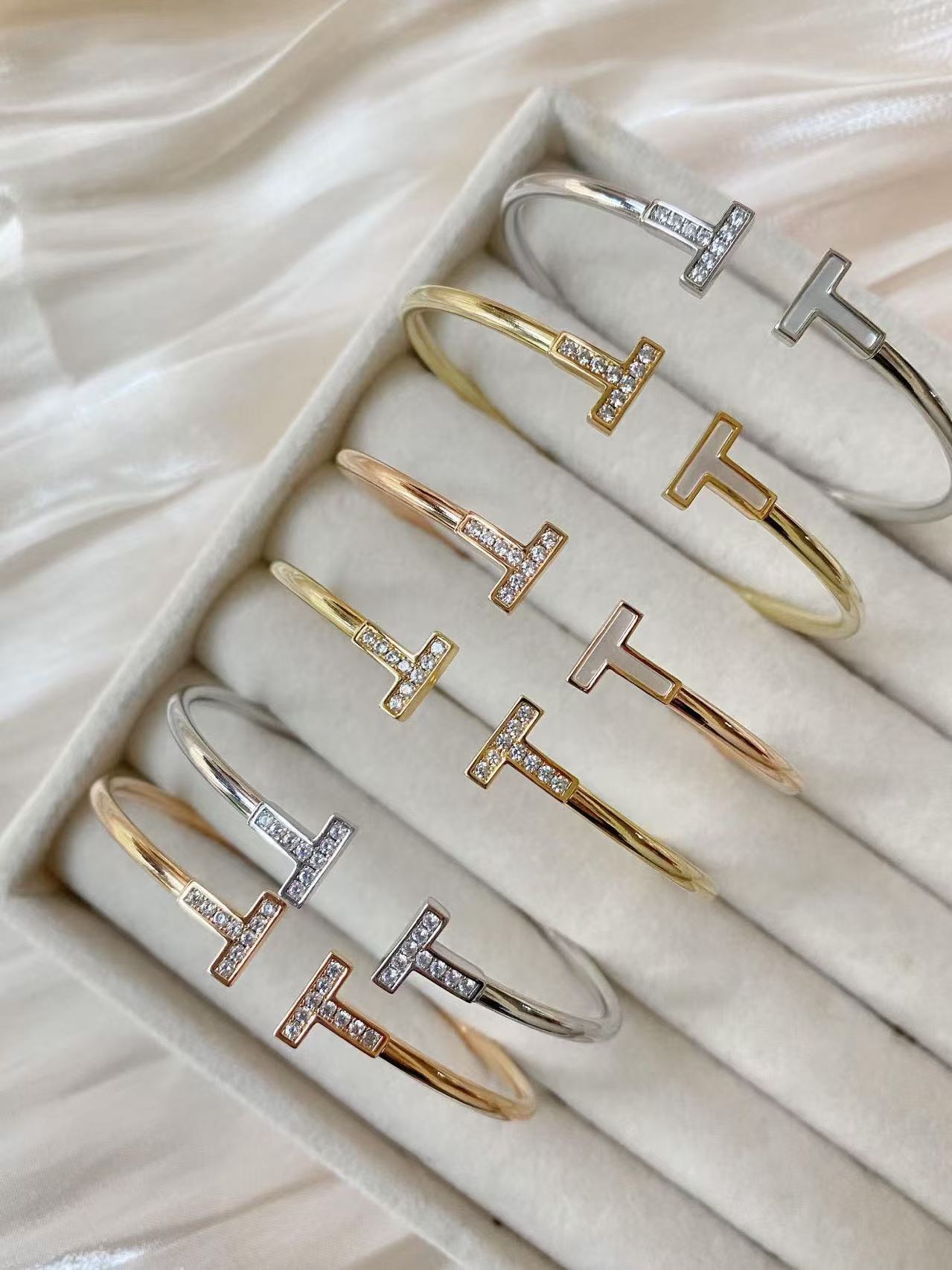 Set of gold and silver 'T' bangles on a soft fabric background