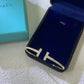 Blue phone case with gold 'H' design on a textured surface next to a Tiffany & Co. box.
