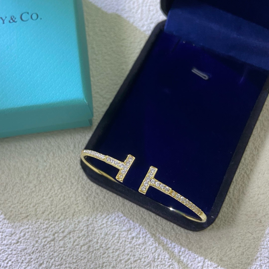 Blue phone case with gold 'H' design on a textured surface next to a Tiffany & Co. box.
