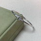 Silver bracelet with a cross design on a green box