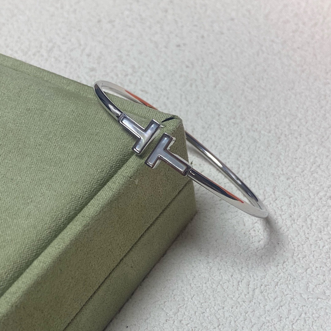 Silver bracelet with a cross design on a green box
