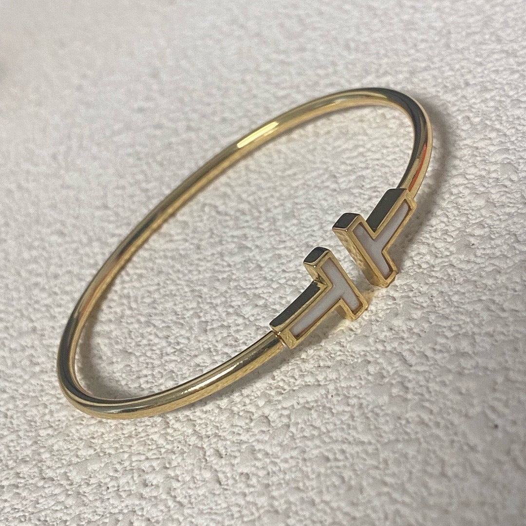 Gold bracelet with a unique design on a light gray background