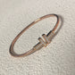 Rose gold bracelet with a logo on a light gray background