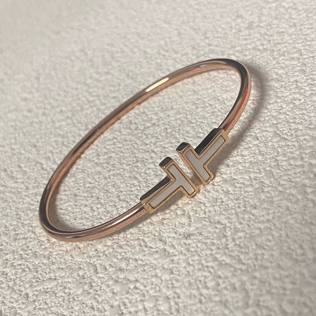 Rose gold bracelet with a logo on a light gray background