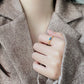 Close-up of a hand wearing a gold ring with a blue gemstone, against a textured brown fabric background.