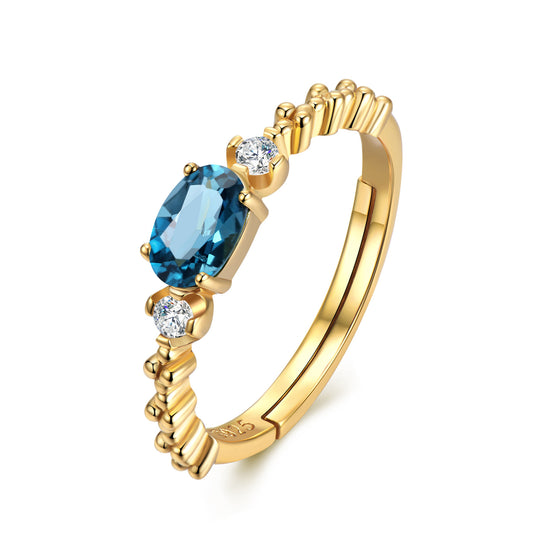 Gold ring with a blue gemstone and diamonds on a white background