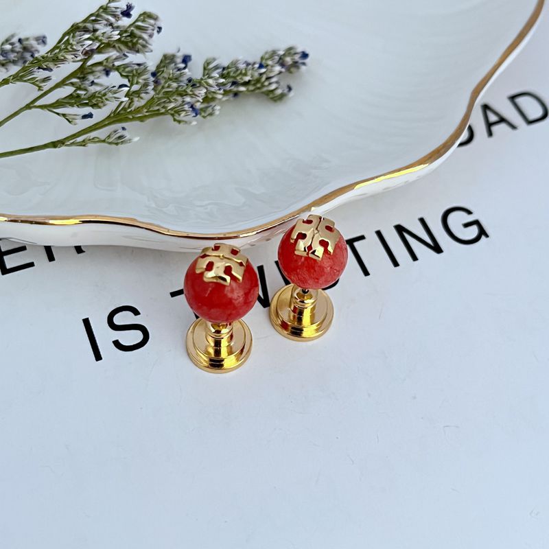 Macro view focusing on the precise engraving and finish of the Double T logo and the smooth, luminous surface of the pearl.