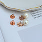 Clean, front-facing shot of a single earring against a soft, neutral background, showcasing the Double T logo above the pearl drop.