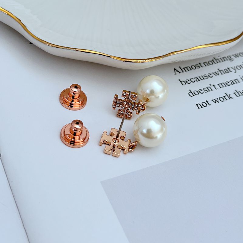 Clean, front-facing shot of a single earring against a soft, neutral background, showcasing the Double T logo above the pearl drop.