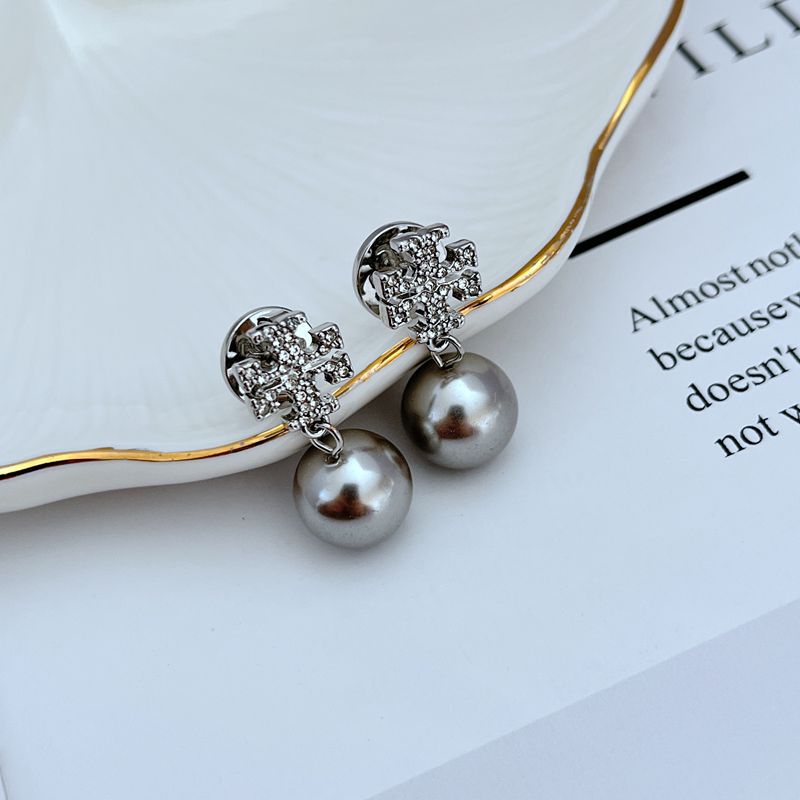 Macro view focusing on the engraved details of the Double T logo and the smooth, luminous surface of the pearl.