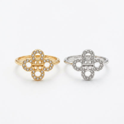 Two interlocking clover-shaped rings, one in yellow gold and one in silver, both adorned with small clear stones, shown on a plain light gray background.