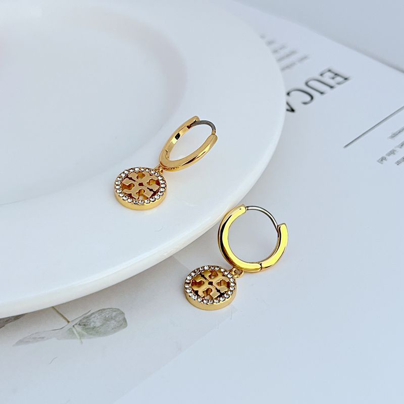 Clean, bright shot of a single hoop against a dark background, making the gold metal and sparkling crystals on the Double T logo stand out dramatically.