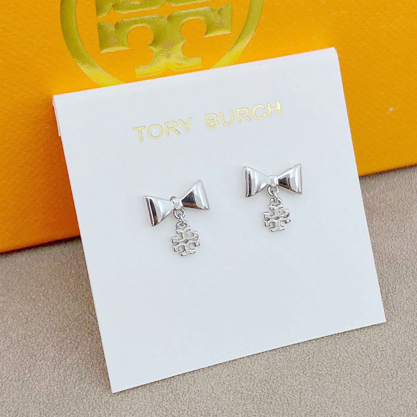 Extreme close-up of one earring showing the bow detailing and polished finish.