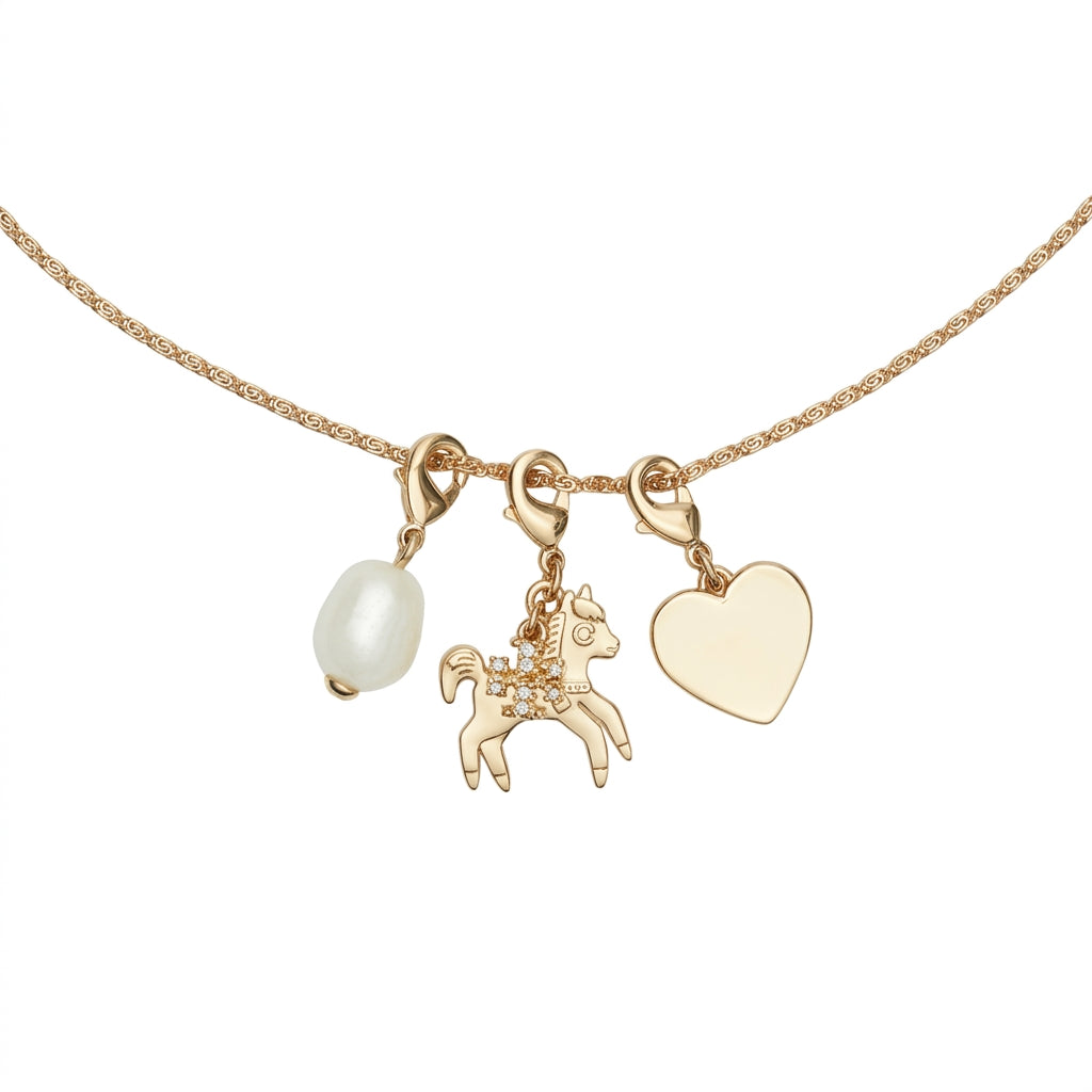 A gold chain necklace featuring three charms: a white pearl bead, a small gold unicorn charm with clear rhinestones, and a flat gold heart charm, shown against a plain white background.