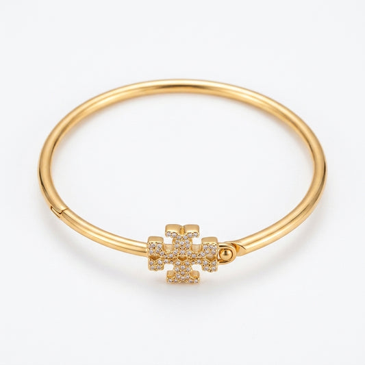 A gold-plated bangle bracelet with a small flower-shaped charm paved with clear stones, shown on a clean white background.