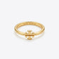 A gold ring featuring a small interlocking T logo charm on the front, with 'TORY BURCH' engraved inside the band, set against a clean white background.