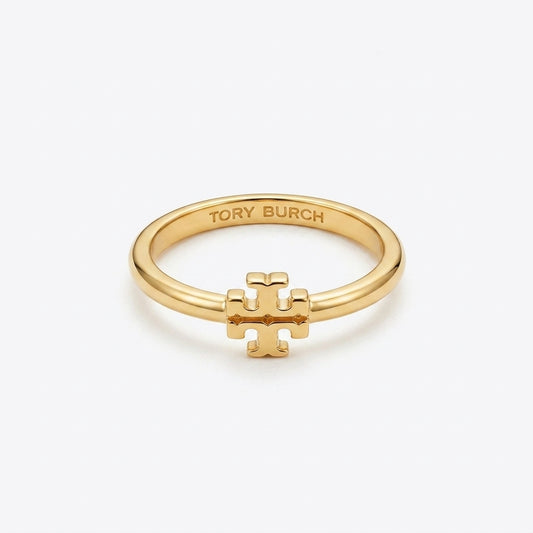 A gold ring featuring a small interlocking T logo charm on the front, with 'TORY BURCH' engraved inside the band, set against a clean white background.