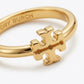 A gold ring featuring a polished interlocking cross logo charm, with the brand name 'TORY BURCH' engraved on the inner band, set against a clean white background.